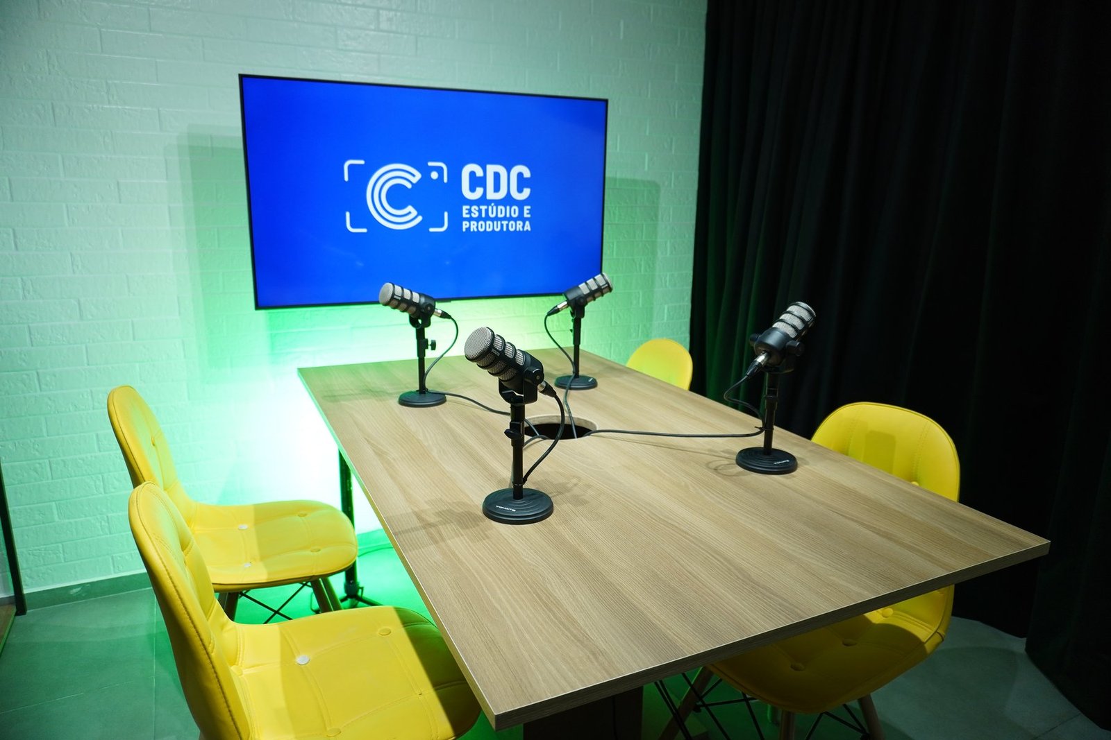 Estúdio da CDC com iluminação verde e cadeiras amarelas